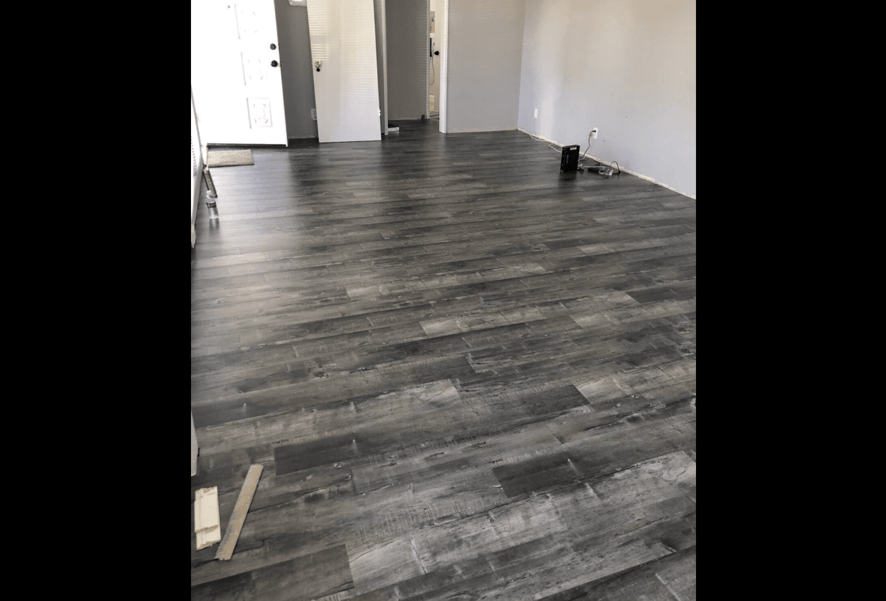 Wide room with dark plank flooring installation in progress